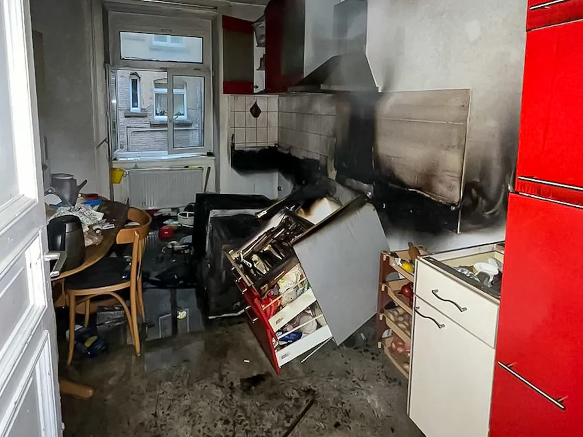 Küche nach einem Brand: verrußte Wand, beschädigte Möbel und Hausrat