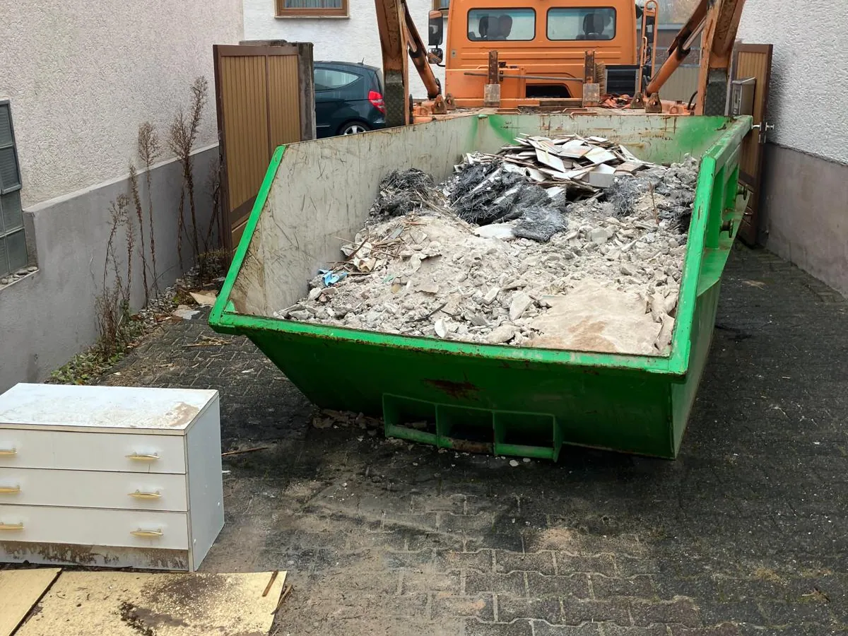 Absetzcontainer mit sortiertem Bauschutt vor dem Objekt