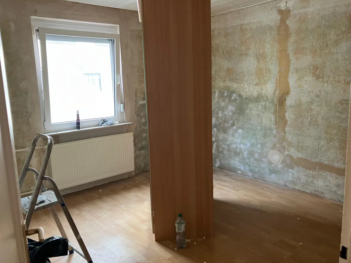 Zimmer mit entfernten Tapeten, vorbereitet für die Renovierung